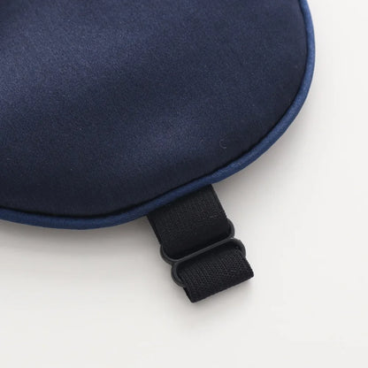 a close-up of a dark blue silk sleeping mask on a white background